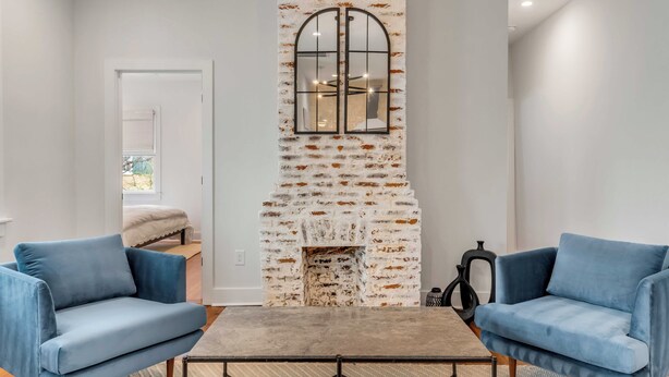 A modern living room with a brick fireplace, two blue armchairs, and a coffee table. - The Philip's Suite, newly renovated 3 Bed/3 EnSuite Bath, 1 Block to King (Charleston)