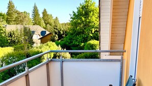 Ein Balkon mit Holzboden, einem runden Tisch und zwei blauen Stühlen.