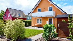 Ein zweistöckiges Haus mit Balkon, rotem Dach und Holzzaun.