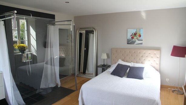 Ein modernes Schlafzimmer mit einem großen Bett, einem begehbaren Kleiderschrank und einer Duschkabine aus Glas.