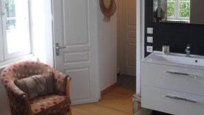 Ein Zimmer mit einem weißen Schminktisch, einem Stuhl mit Punkten und einer weißen Tür sowie einem Fenster.