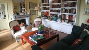 Ein Wohnzimmer mit Kamin, Bücherregalen, einem Couchtisch und einer Couch.
