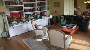 Ein Wohnzimmer mit Couch, zwei Stühlen, einem Bücherregal und einem Holztisch.