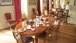 Ein Esszimmer mit Holztisch, gedeckt für das Frühstück, darunter Croissants, Kaffee und Saft.