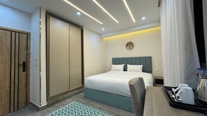 Ein Hotelzimmer mit Bett, Schreibtisch mit Tablett und persönlichen Gegenständen, Kleiderschrank und Badezimmertür.