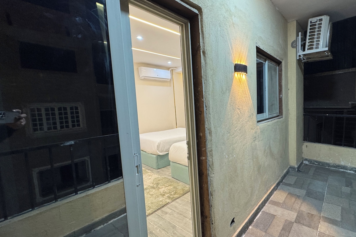 An interior corridor with a sliding door leading to a room with a bed and an air conditioning unit mounted on the wall.
