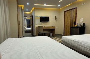 Habitación de hotel con dos camas, un televisor, un mueble de madera, una mesita redonda y una puerta que da a otra habitación.
