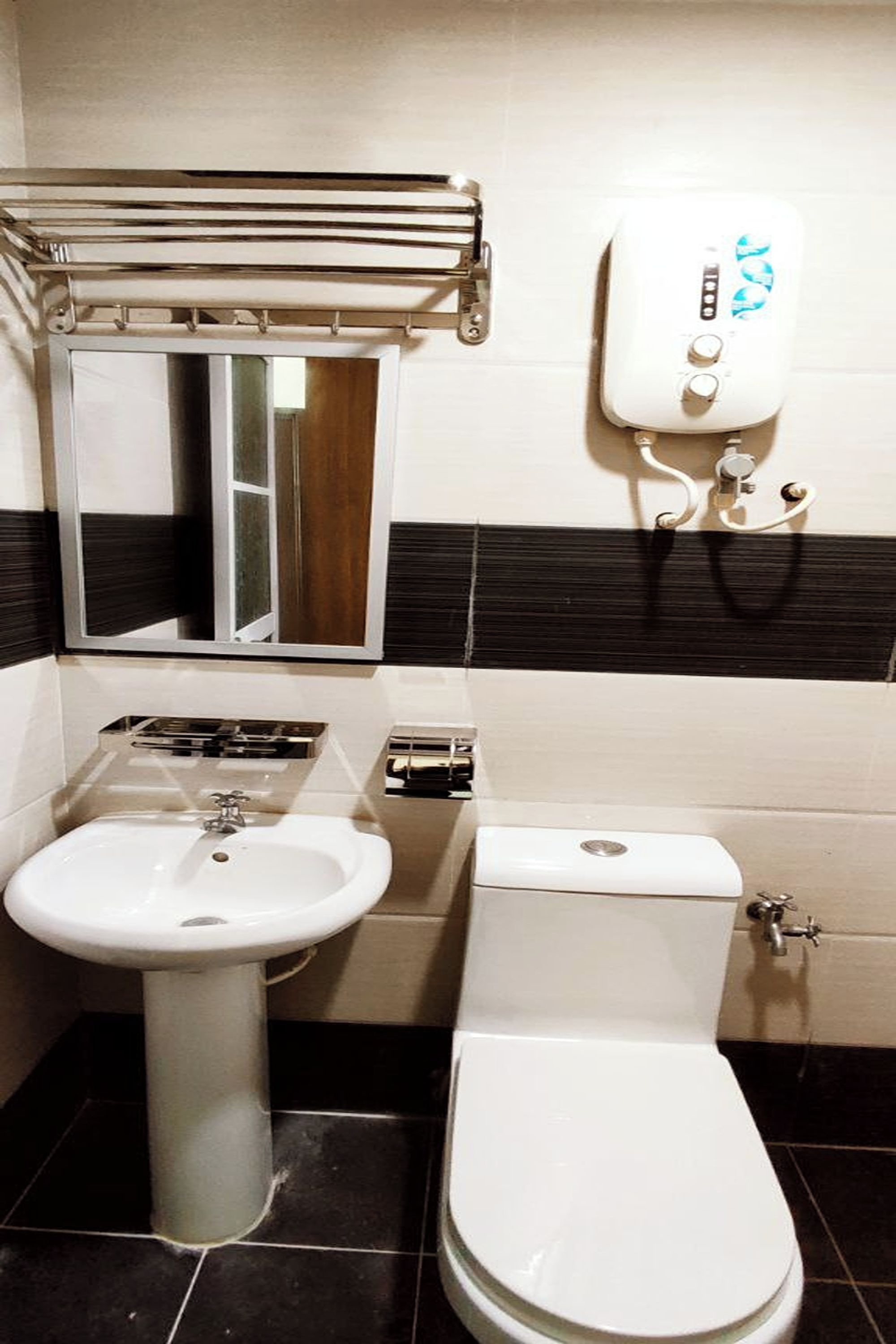 Et badeværelse med et håndvask på fod, toilet, bøjle til håndklæder og et spejl.