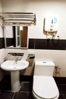 Un baño con lavamanos pedestal, inodoro, toallero y espejo.