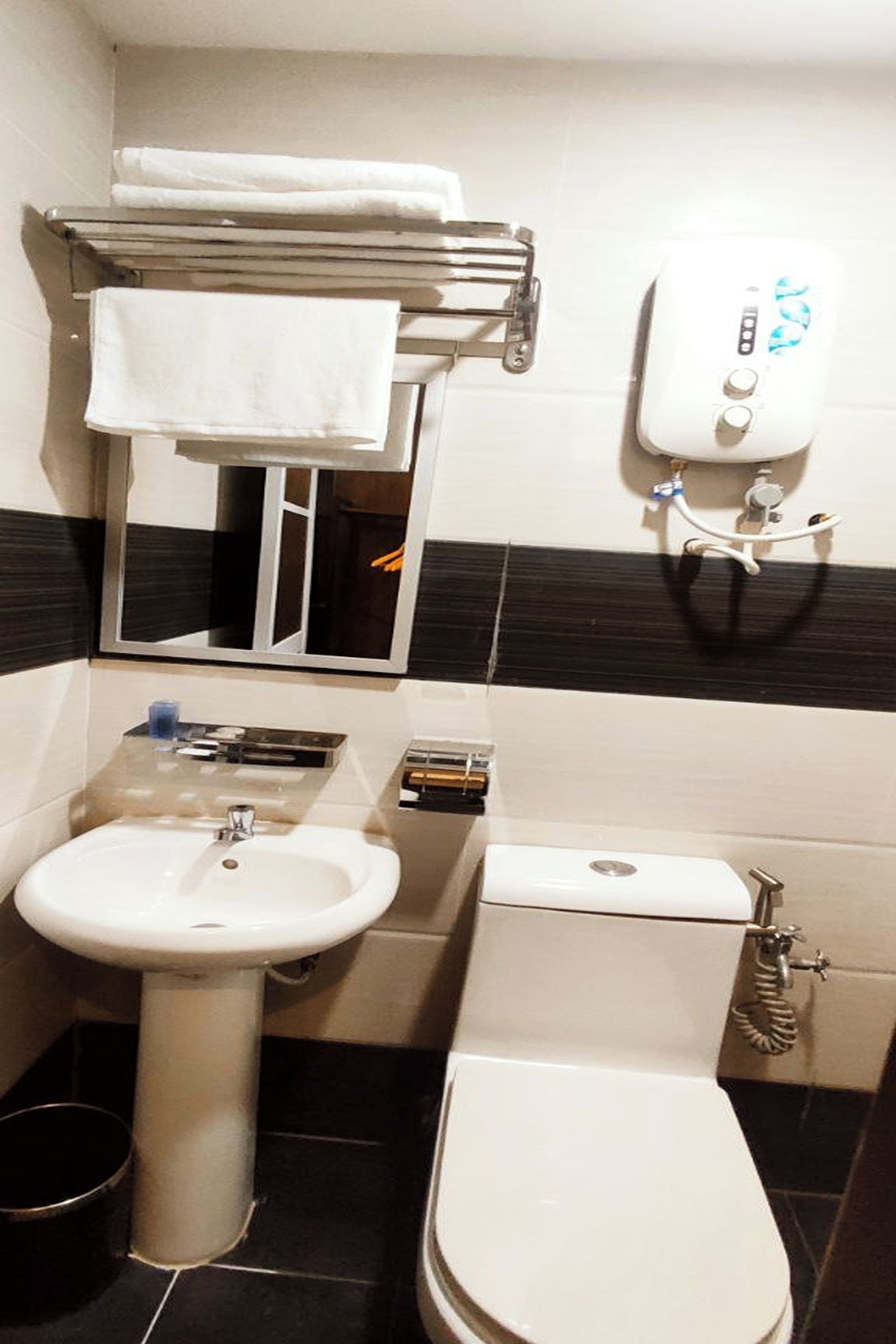 Un baño pequeño con lavamanos, inodoro y toallero.