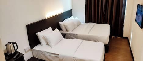 Una habitación de hotel con dos camas, una mesita de noche con un hervidor y un televisor en la pared.