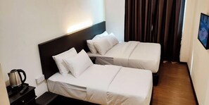 Una habitación de hotel con dos camas, una mesita de noche con un hervidor y un televisor en la pared.