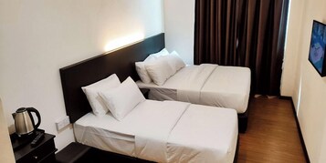 Una habitación de hotel con dos camas, una mesita de noche con un hervidor y un televisor en la pared.