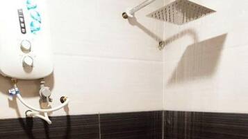 Baño en esquina con inodoro, ducha y secamanos fijado a la pared.