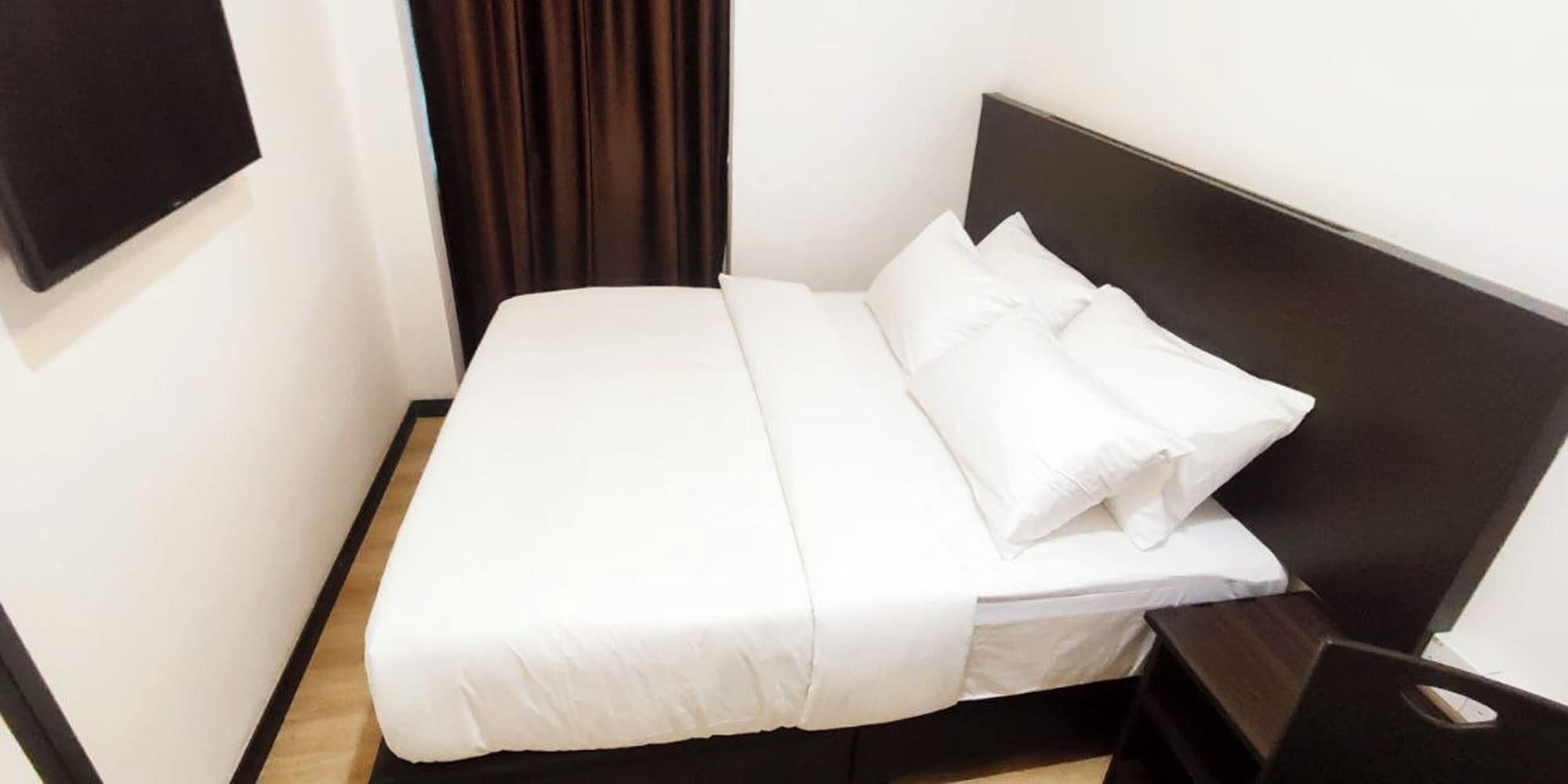 Ein ordentlich bezogenes Bett mit weißer Bettwäsche in einem Hotelzimmer.