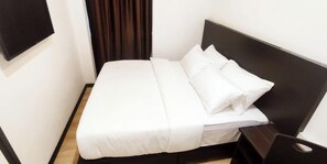 En välordnad säng med vita sängkläder i ett hotellrum.