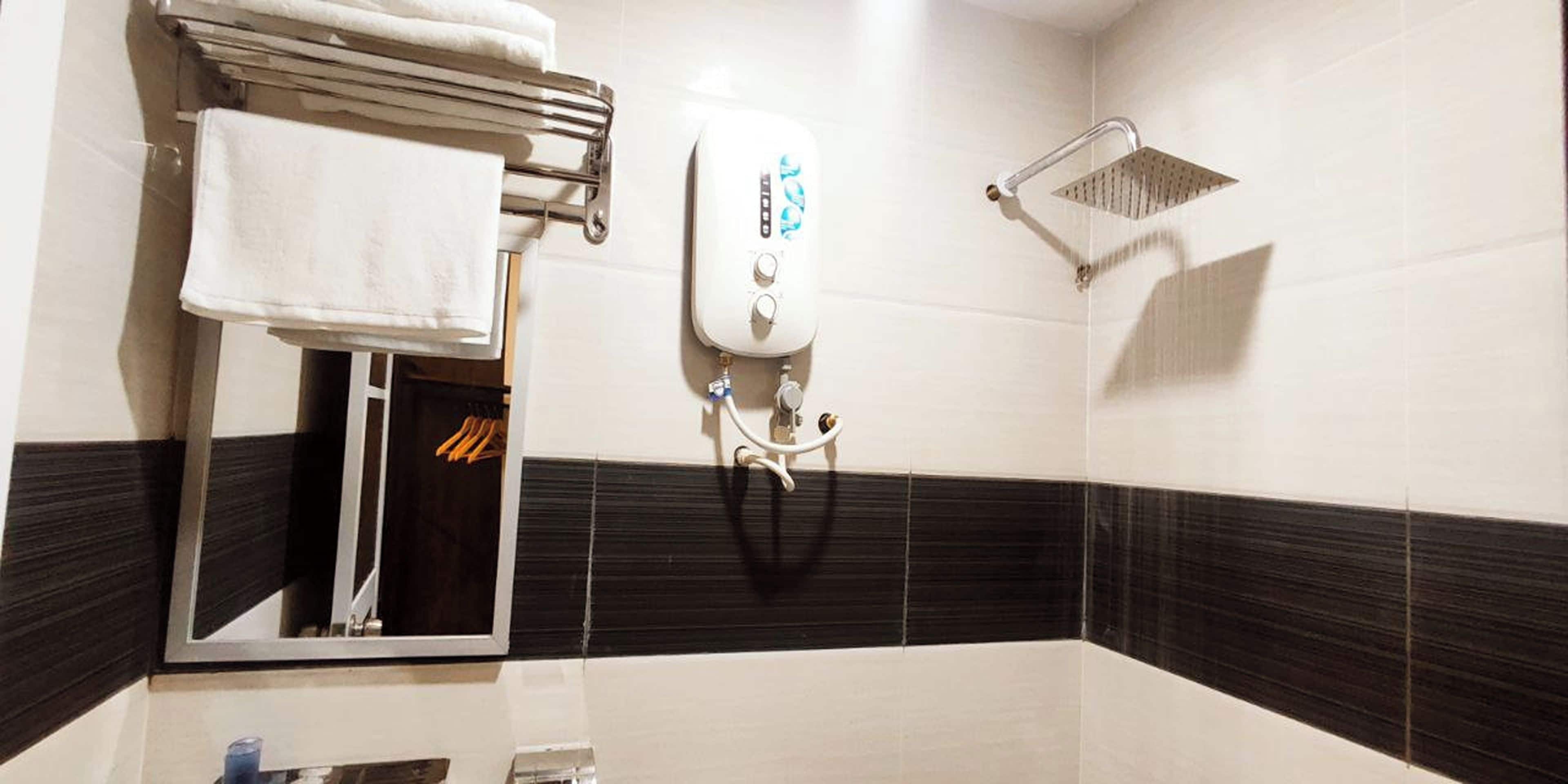 A bathroom with a towel rack, a showerhead, and a hand dryer.