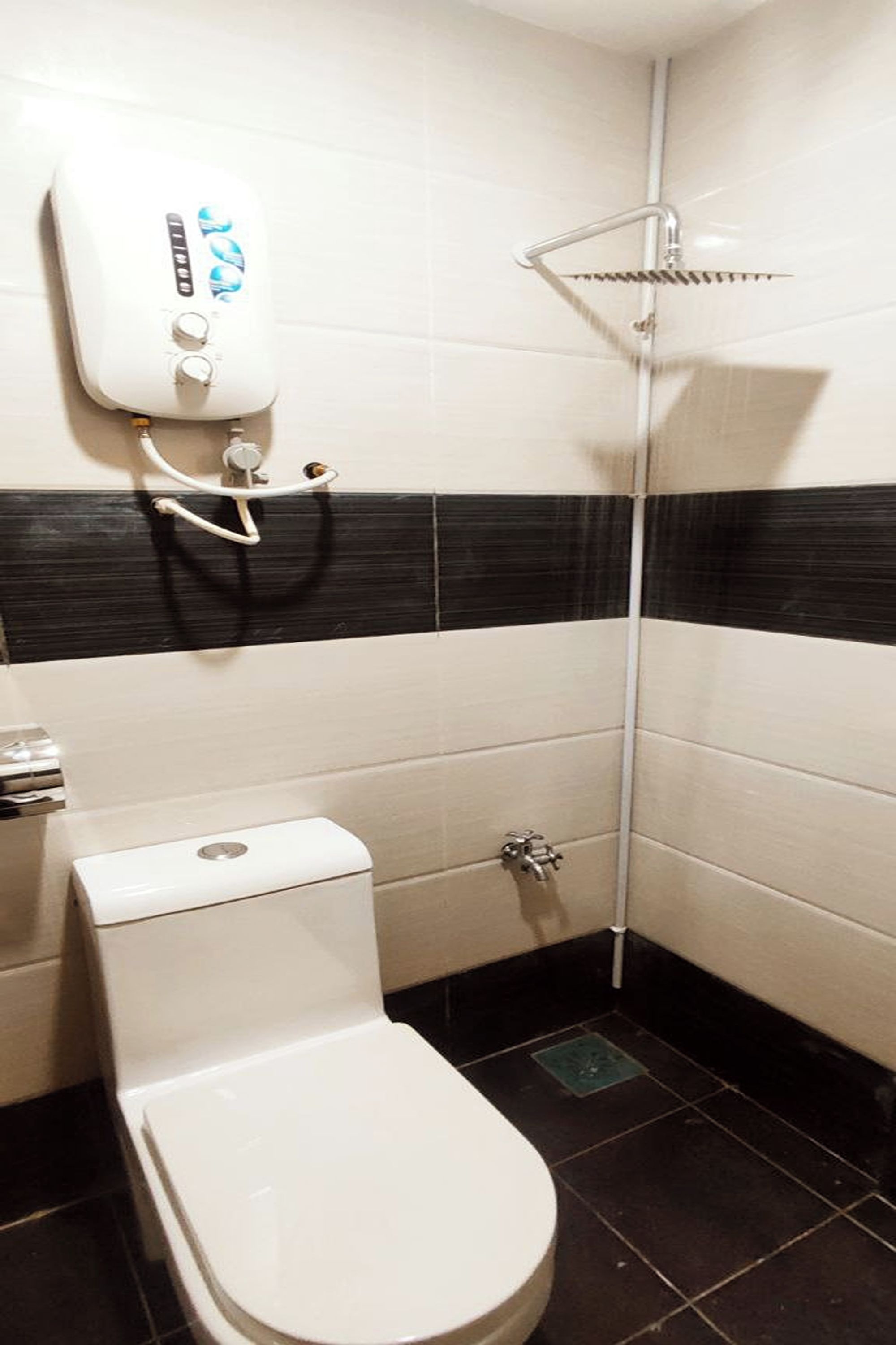 A small, compact bathroom with a toilet, a shower, and a wall-mounted water heater.
