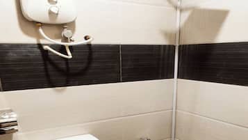 A small, compact bathroom with a toilet, a shower, and a wall-mounted water heater.