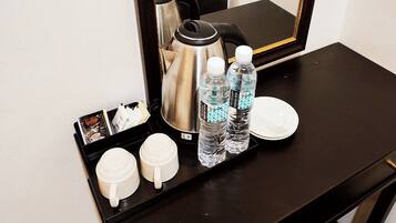 A tray with two white mugs, two water bottles, a coffee pot, and a plate on a black table.