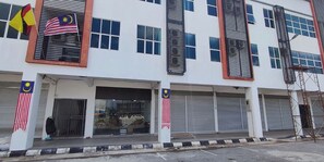 A multi-story building with several closed shutters, a flag on the left, and a flag on the right. - ABA Hotel Sarawak By Zuzu (Kota Samarahan)