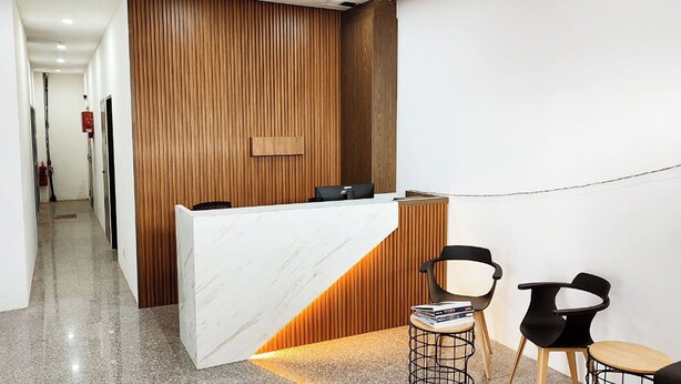 A reception area with a marble counter, wooden panel wall, and two black chairs with a small table. - ABA Hotel Sarawak By Zuzu (Kota Samarahan)