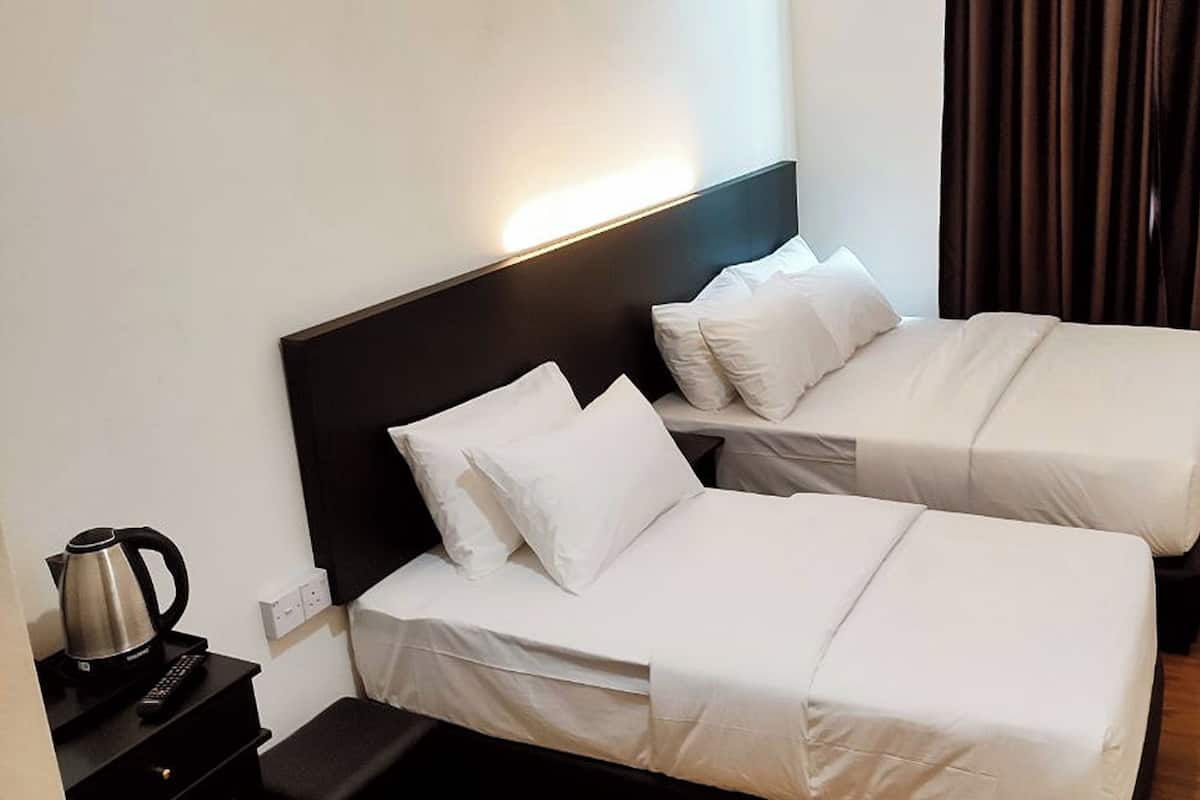 Quarto de hotel com duas camas de solteiro, uma mesa de cabeceira com chaleira e uma TV fixada na parede.