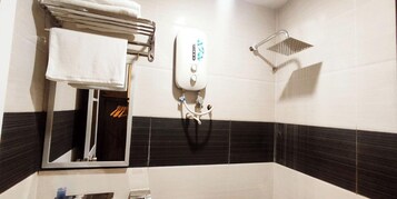 Un baño con un perchero para toallas, un cabezal de ducha manual y un espejo.