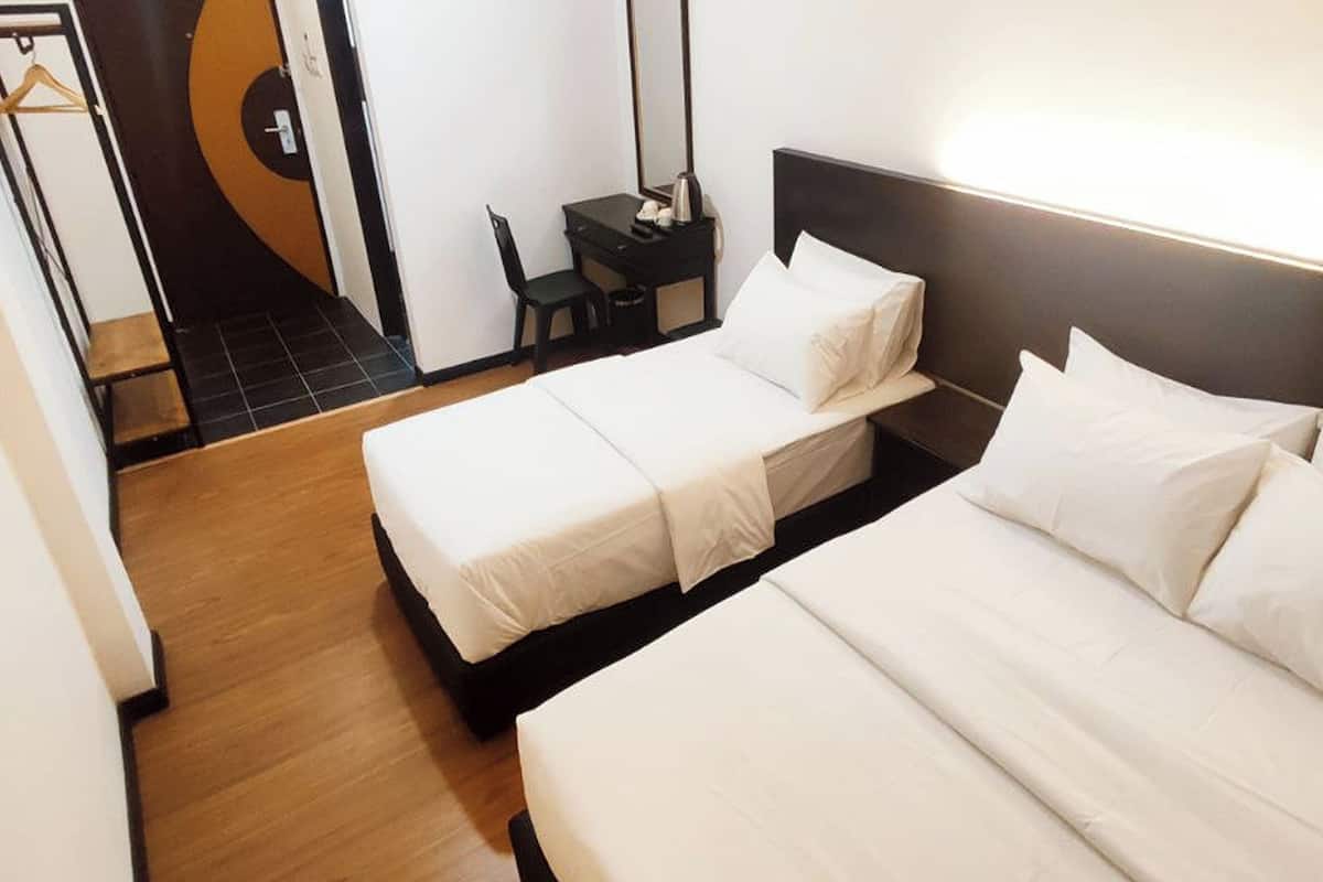 Quarto de hotel com duas camas, uma escrivaninha e uma cadeira.