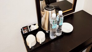 A tray with two white mugs, two water bottles, a coffee pot, and a plate on a black table. - ABA Hotel Sarawak By Zuzu (Kota Samarahan)