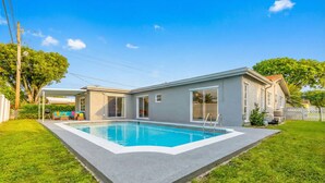 A modern house with a swimming pool, a covered patio, and a well-maintained lawn. - Private Pool, Patio & BBQ Near Beaches & Casino (Margate)