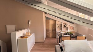 A modern, well-lit room with a dining area, a sofa, and a small kitchen area. - [SKY Cinema] Elegance and design in the heart of Trento (Trento)