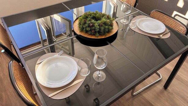 A dining table with a glass top, surrounded by wicker chairs, and a decorative centerpiece. - [SKY Cinema] Elegance and design in the heart of Trento (Trento)
