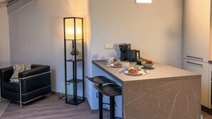 A modern kitchen with a marble countertop, a coffee maker, and a bowl of fruit. - [SKY Cinema] Elegance and design in the heart of Trento (Trento)