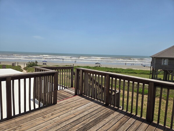 Eine Holzterrasse mit Blick auf Strand und Meer.