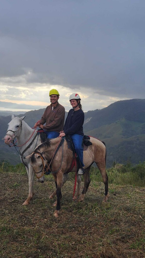 Two people on horseback in a mountainous area.