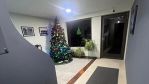 A hallway with a Christmas tree, framed pictures on the wall, and a door leading to another room. - Skyline Suites (La Paz)