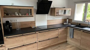 Una cocina moderna con armarios de madera, encimera negra y ventana que deja entrar luz natural.