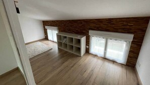 Habitación con piso de madera, estantería empotrada y ventana con persianas.