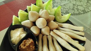 Une assiette contenant divers amuse-gueules, notamment des gressins, des rondelles de concombre et deux petits bols de sauce pour tremper.