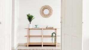 A minimalist hallway with a wooden console table, a potted plant, a mirror, and a woven wall decoration. - The Stately Way, Wallaroo (Wallaroo)