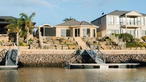 A waterfront property with a stone retaining wall, a dock, and a house with a large balcony. - The Stately Way, Wallaroo (Wallaroo)