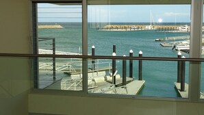 Vista desde un balcón sobre un puerto deportivo con barcos, muelles y cielo despejado.