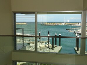 Vista da un balcone su una marina con barche, pontili e cielo sereno.