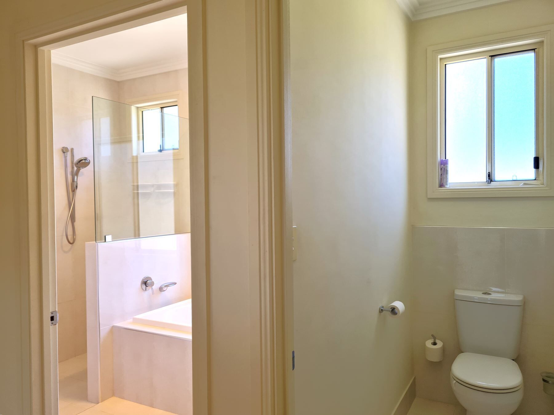 Une salle de bain comprenant des toilettes, une fenêtre et un espace douche.