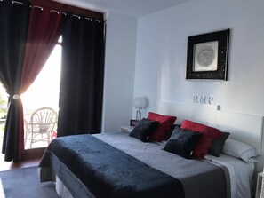Ein Schlafzimmer mit einem Bett, einem gerahmten Bild an der Wand und einem Sessel am Fenster.