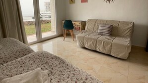 A bedroom with a large bed, a sofa, and a chair. There is a view of the outdoors through a glass door. - Torre De La Roca (Torremolinos)