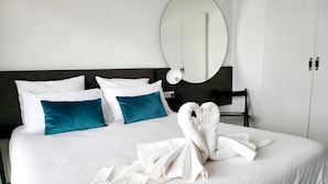 A hotel room with a large bed, white bedding, teal pillows, and a heart-shaped towel arrangement. - Torre De La Roca (Torremolinos)