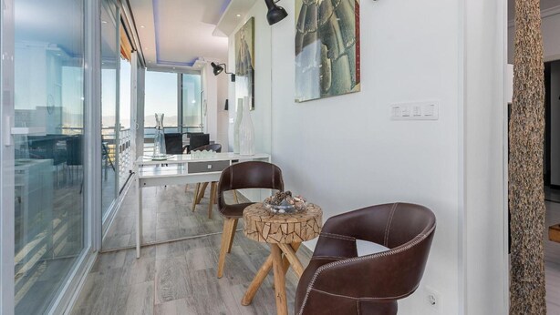 A modern dining area with a glass partition, wooden flooring, and leather chairs. - Torre De La Roca (Torremolinos)