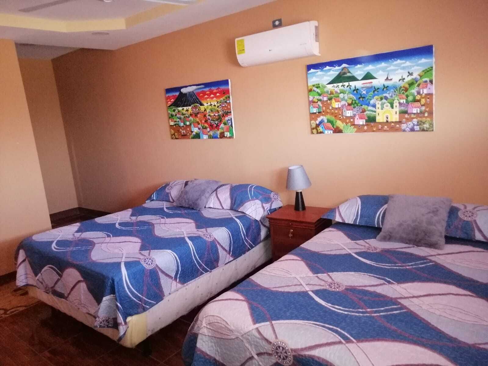 A hotel room with two beds, a nightstand, and two wall paintings.